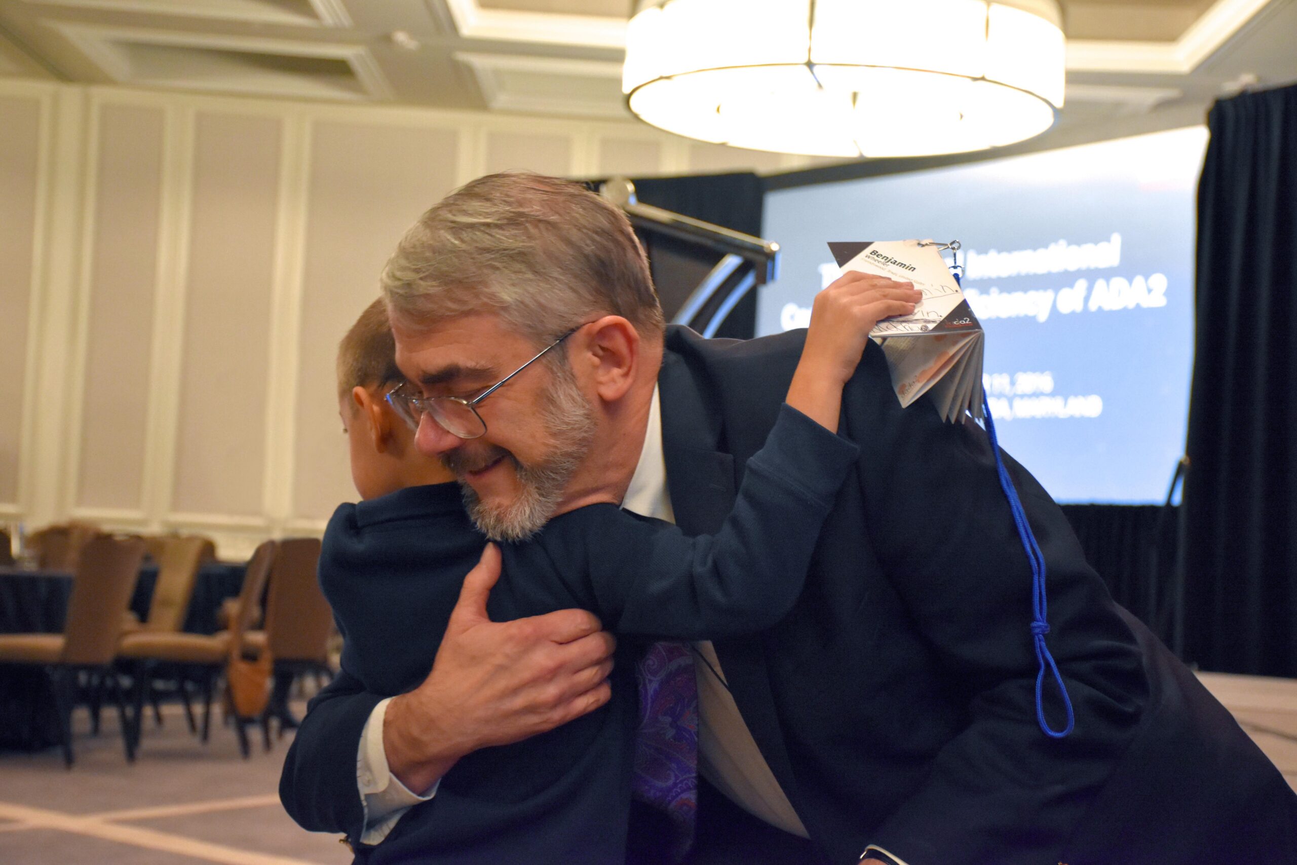 Dr. Dan Kastner warmly embracing a young DADA2 patient