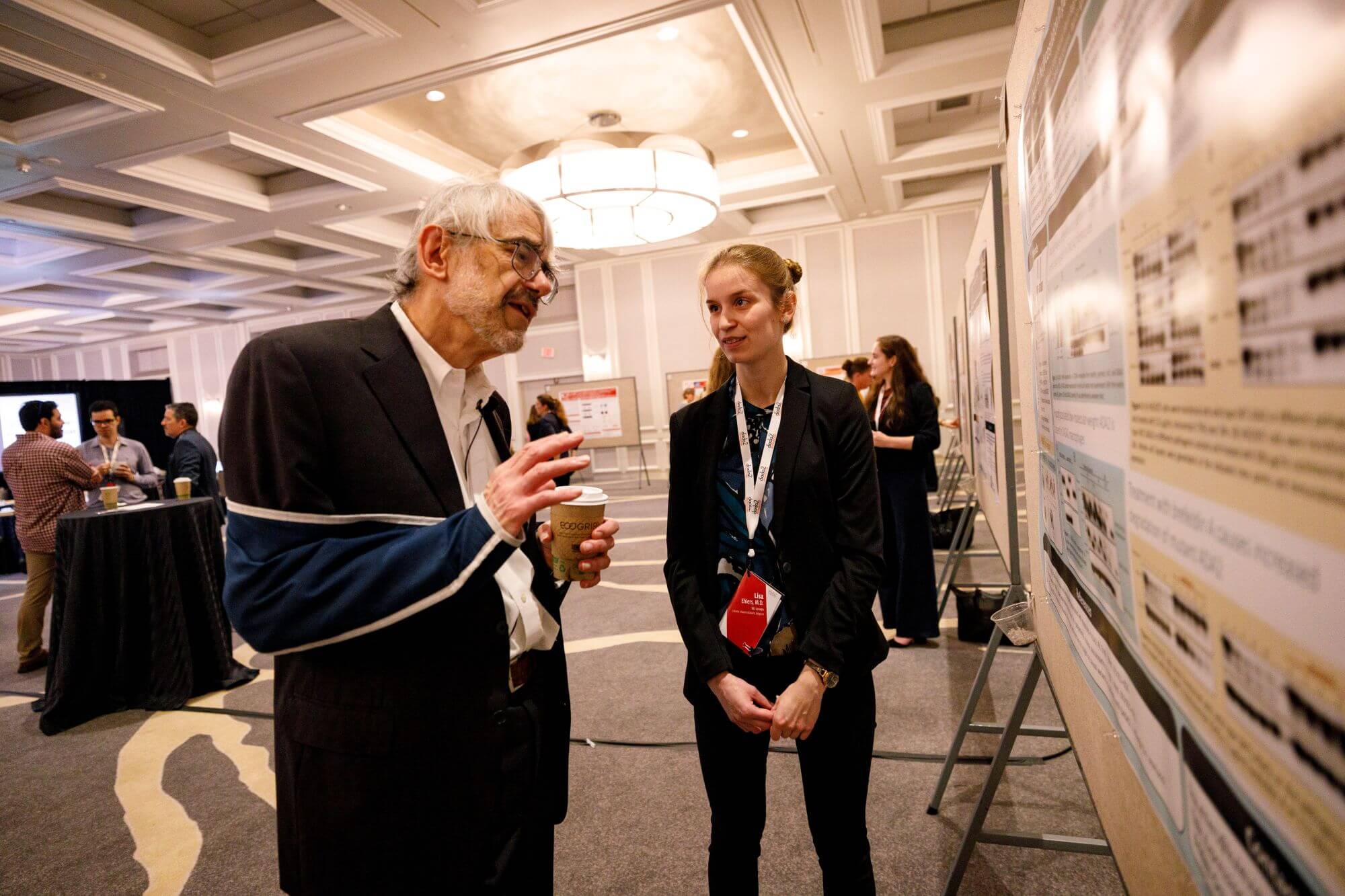 Dr. Dan Kastner discussing research with a scientist at a conference poster session